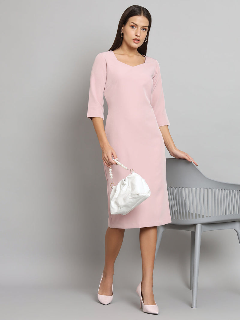 Stretch pencil dress in baby pink styled with white handbag and heels.