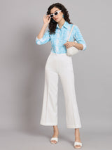 Marble print collared shirt in blue worn with white pants.