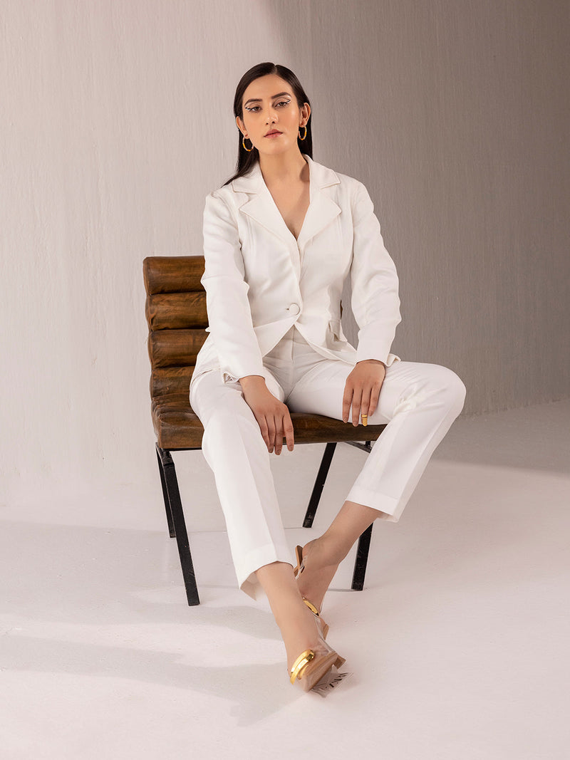 Elegant woman in off-white suit sitting on a chair.