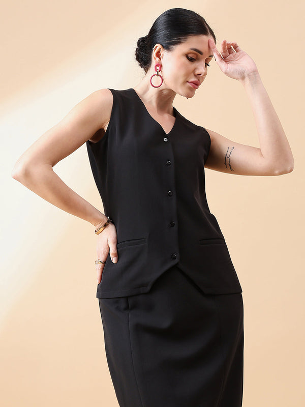 Elegant woman modeling black waistcoat top against a soft background.